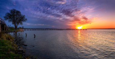 Sakin bir gölün üzerinde güzel, renkli bir gün batımı.