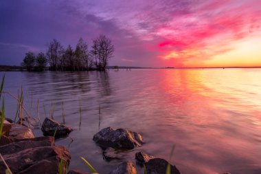 Sakin bir gölün üzerinde güzel, renkli bir gün batımı.