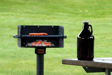 Growler in Front of Charcoal Grill with Blurred Background clipart