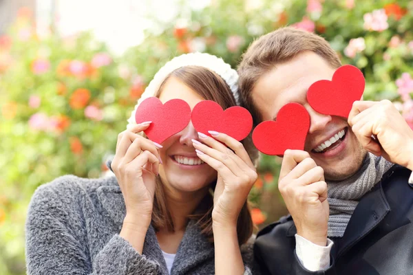 Happy couple covering eyes with hearts — Stock fotografie