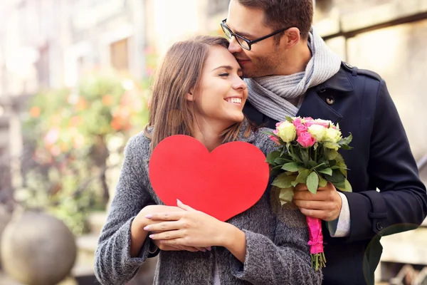 Junges Paar mit Blumen und Herz — Stockfoto