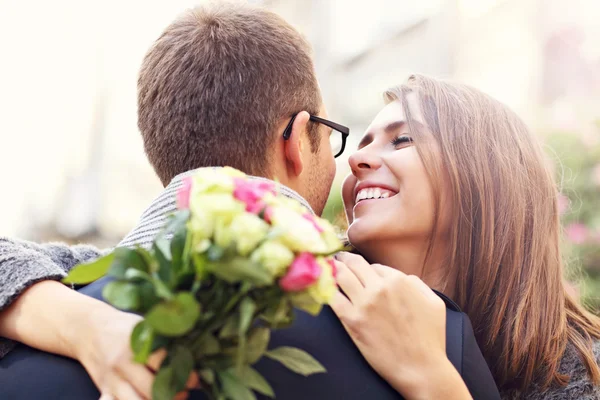 Femme avec des fleurs donnant câlin à son homme — Photo