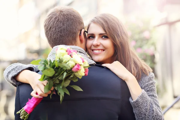 Mulher com flores dando abraço ao homem — Fotografia de Stock