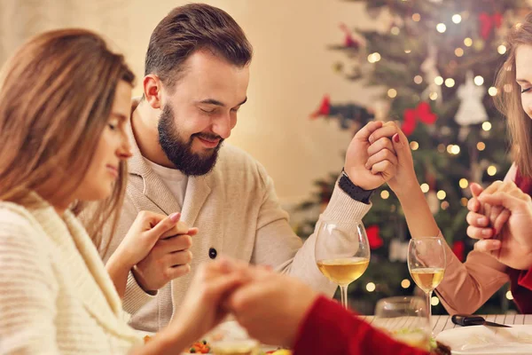 Grupo de amigos rezando sobre a mesa de Natal — Fotografia de Stock