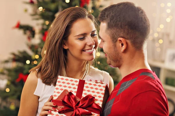 Casal com presente sobre a árvore de Natal — Fotografia de Stock
