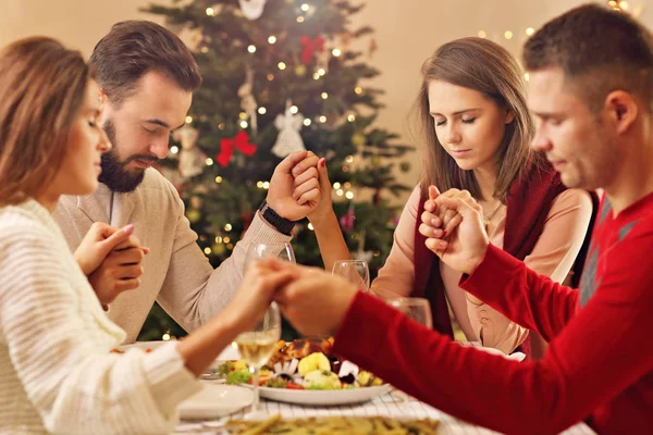 Grupo de amigos rezando sobre la mesa de Navidad — Foto de Stock