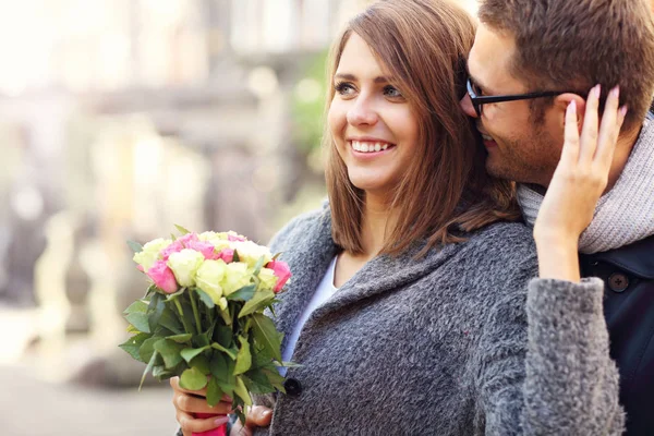 Unga par med blommor kyssar i staden — Stockfoto