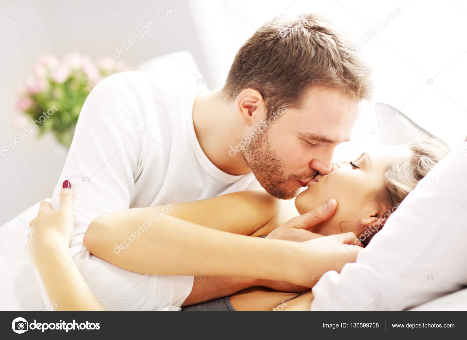 Fotos de Pareja joven besándose en la cama Imagen de