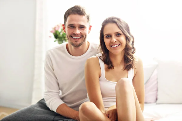 Pareja feliz sentada en la cama — Foto de Stock