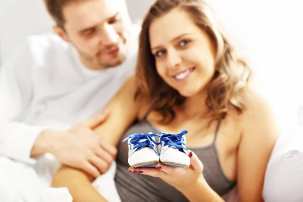 Pareja en la cama con zapatos de bebé —  Fotos de Stock