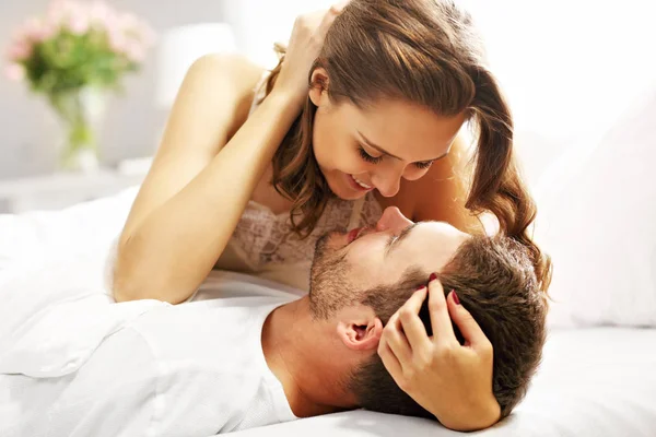 Fiatal pár ölelkezik az ágyban — Stock Fotó