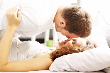 Genç çift yatakta öpüşüyor.