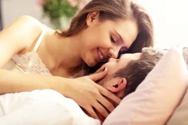 Genç çift yatakta öpüşüyor.