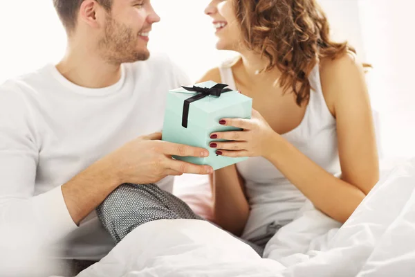 年轻夫妇带着礼物躺在床上 — 图库照片