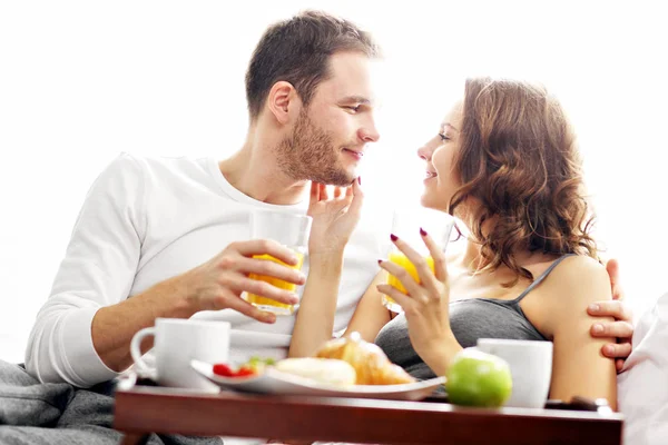 Jovem casal tomando café da manhã na cama — Fotografia de Stock