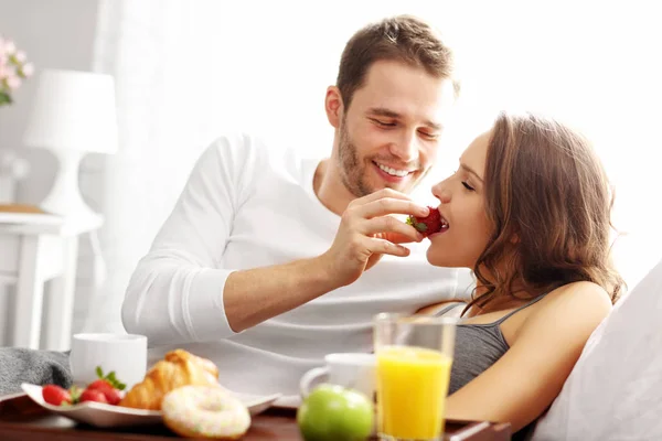 Young couple eating breakfast in bed