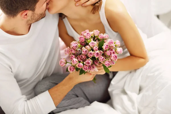 침대에서 여자에 게 꽃을 주는 남자 — 스톡 사진