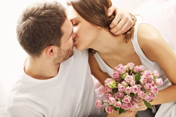 Hombre dando flores a la mujer en la cama —  Fotos de Stock