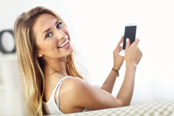 Mujer feliz con teléfono inteligente en el sofá — Foto de Stock