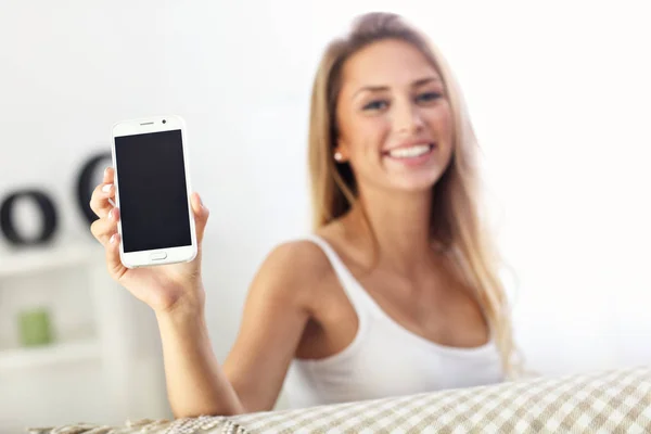 Счастливая женщина со смартфоном на диване — стоковое фото