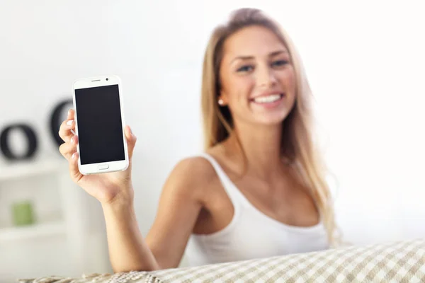 Mujer feliz con teléfono inteligente en el sofá — Foto de Stock