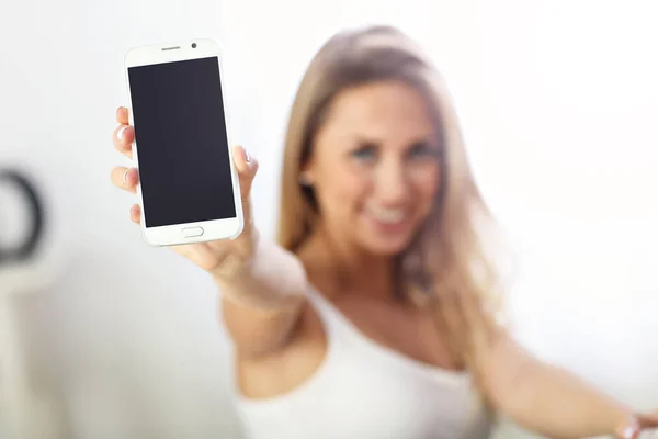 Mujer feliz con teléfono inteligente en el sofá — Foto de Stock