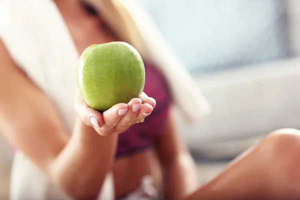 Сидячая женщина ест яблоко дома — стоковое фото