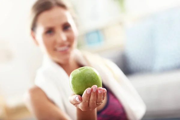 Сидячая женщина ест яблоко дома — стоковое фото