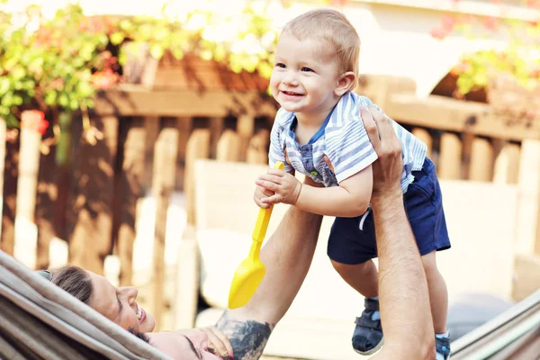 Pais felizes brincando com seu bebê menino na rede — Fotografia de Stock