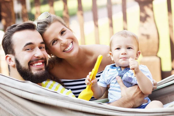 Pais felizes brincando com seu bebê menino na rede — Fotografia de Stock