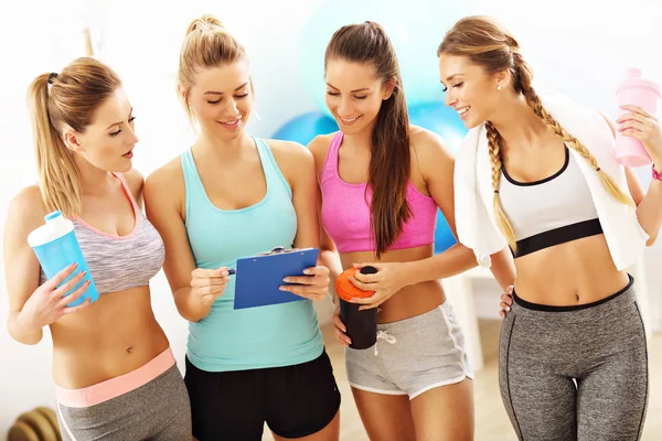 Grupa młodych kobiet, omawiając plan zdrowia na siłowni — Zdjęcie stockowe