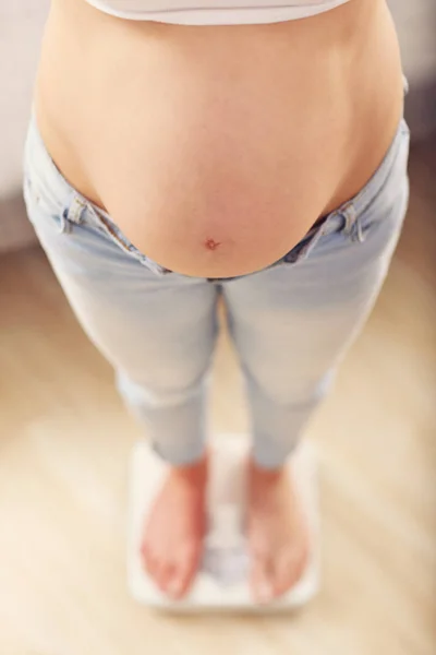 Zwangere vrouw op de weegschaal — Stockfoto