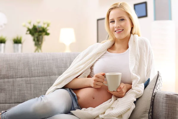 Mujer embarazada feliz descansando en el sofá —  Fotos de Stock
