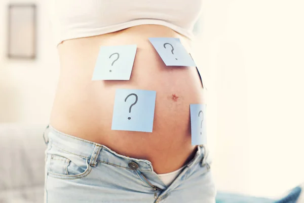 Pregnant woman with question marks — Stock Photo, Image