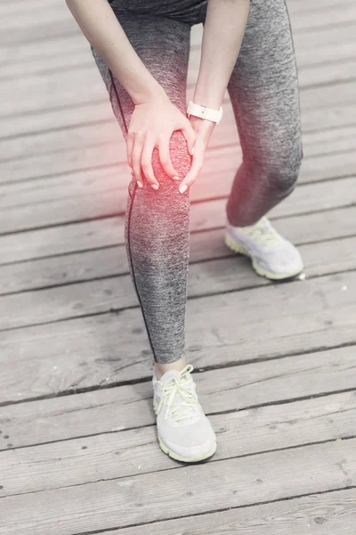 Female athlete runner touching knee in pain outdoors — Stock Photo, Image