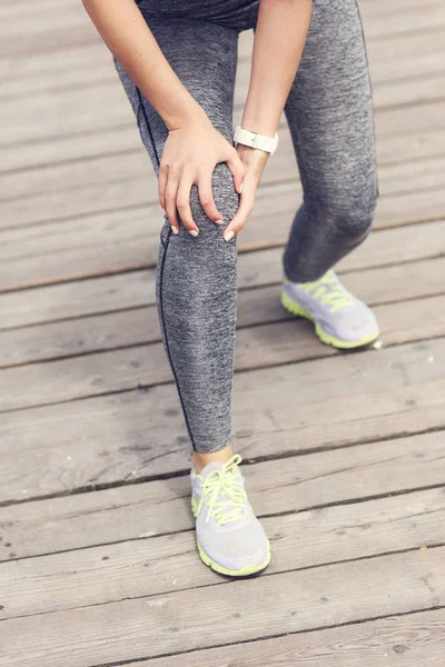 Athlète féminine coureuse touchant le genou dans la douleur à l'extérieur — Photo