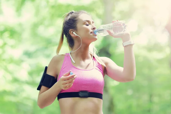 Жінка біжить в лісі з пляшкою води — стокове фото