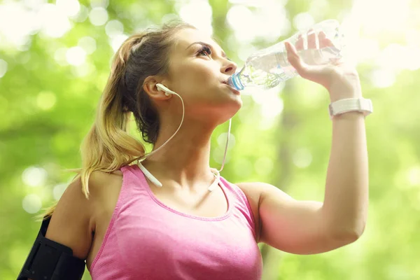 Woman jogging in the forest with bottle of water — Stock Photo, Image