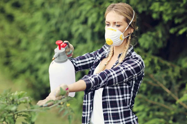 Donna adulta spruzzando piante — Foto Stock
