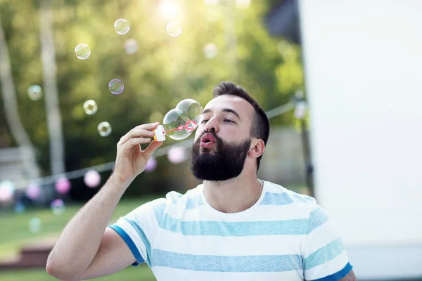 Ung man blåser bubblor utomhus — Stockfoto