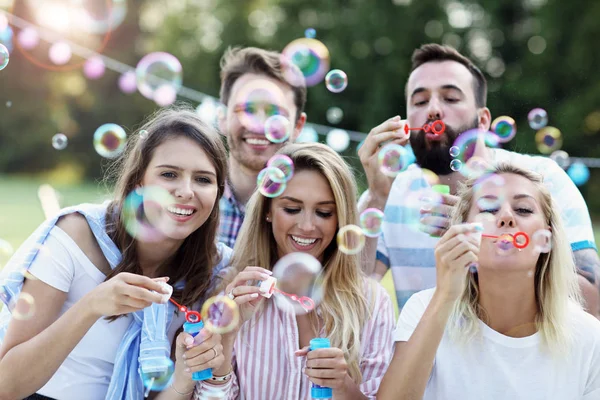 F vänner blåser bubblor utomhus — Stockfoto