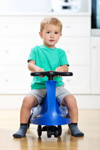 Szczęśliwy chłopiec o zabawki zabawy i jazdy samochód wyścigowy w domu — Zdjęcie stockowe