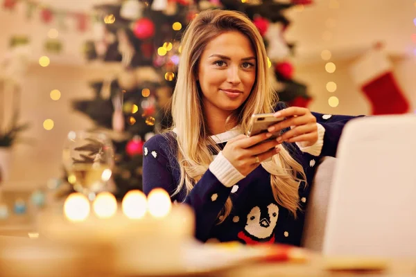 Junge Frau mit Smartphone zu Weihnachten zu Hause — Stockfoto