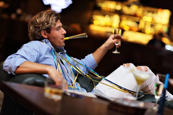 Молодой человек сидит один в баре со стаканом виски — стоковое фото