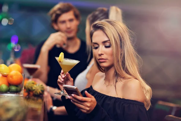 Jonge vrouw vergadering alleen in bar met een coctail — Stockfoto