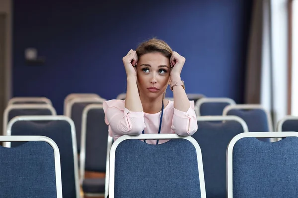 Jovem mulher sentada sozinha na sala de conferências — Fotografia de Stock