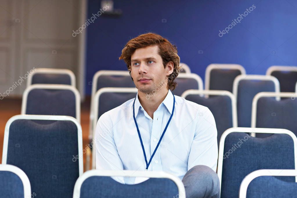 Young man sitting alone in conference room