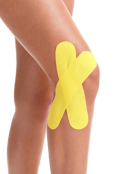 Obrázek ukazující speciální fyzioterapie pásku vložit na zraněné koleno nad bílým pozadím — Stock fotografie