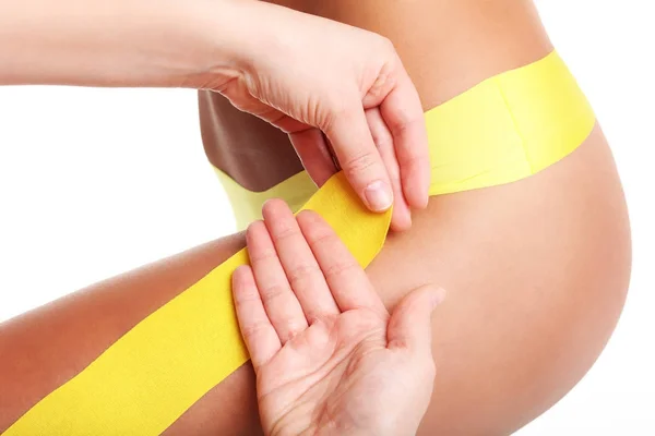 Afbeelding van speciale physio tape zetten gewonde dij op witte achtergrond — Stockfoto