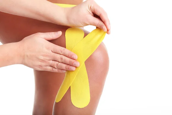 Afbeelding van speciale physio tape zetten gewonde knie op witte achtergrond — Stockfoto